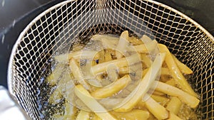 Frying French fries in a deep fryer in hot oil