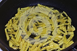 Frying French Fries in sunflower oil in a frying pan