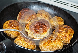 Frying homemade meatballs in black iron pan