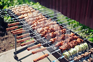 Frying meat vegetables and mushrooms skewered on a large barbecue in the sun, the concept of spring or summer outdoor recreation