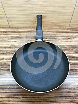 Frying pan with black surface and black plastic handle