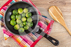 Frying pan with brussels sprouts on napkin, wooden spoon