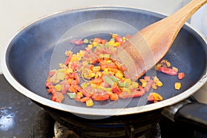 Frying pan with chopped bell pepper and spices on gas stove