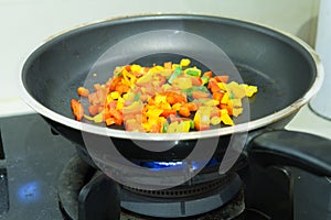 Frying pan with chopped bell pepper and spices on gas stove