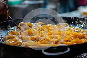 A frying pan filled with onions being cooked on a stovetop, producing a delicious aroma, Saffron-flavored hot jalebis being fried