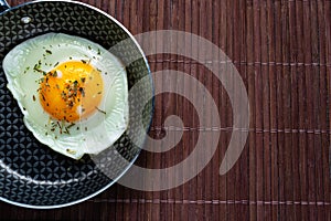 Frying pan with fried egg on a bamboo table