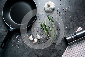 Frying pan with garlic and pepper on black background.