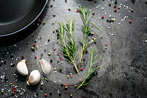 Frying pan with garlic and pepper on black background.