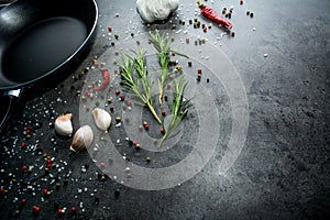 Frying pan with garlic and pepper on black background.