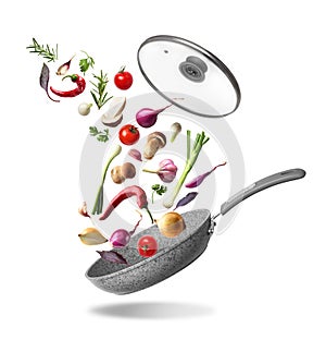 Frying pan with lid and flying vegetables, isolated on white background