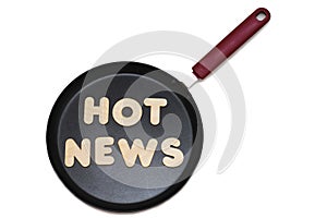 Frying pan with the phrase hot news made of wooden letters. News preparation concept. Isolate on white background, photography