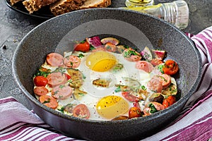 Frying pan with tasty cooked egg, sausages and vegetables on grey table
