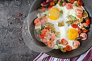 Frying pan with tasty cooked egg, sausages and vegetables on grey table