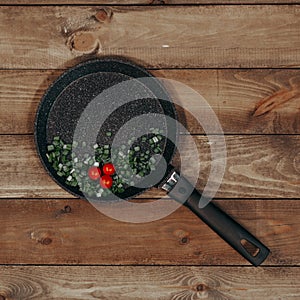 Frying pan with tomatoes and greens on a lerevyanny table