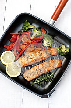 Frying pan with two salmon steaks and herbs