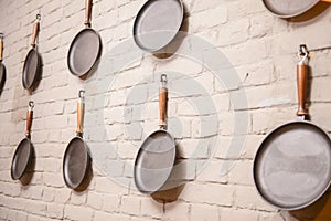 Frying pans against white brick wall. Empty pans over white background. Textured wall banner