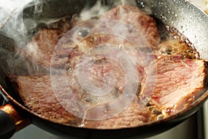 Frying veal in a pan with vapour