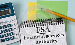 FSA - an abbreviation in a white notebook on the background of a calculator, pencil, colored pieces of paper