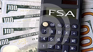 FSA - acronym written on a calculator on the background of banknotes