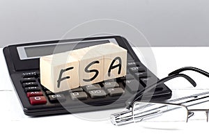 FSA concept on wooden cubes on calculator on white background
