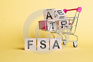 fsa - flexible spending account - letter pices on the wooden cubes, yellow background