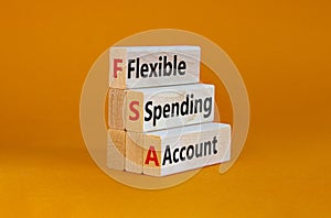 FSA flexible spending account symbol. Concept words FSA flexible spending account on wooden blocks on a beautiful orange photo