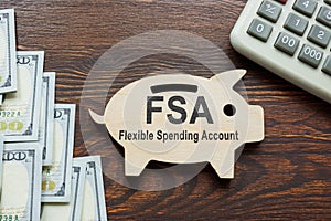 FSA flexible spending account words on wooden piggy bank.