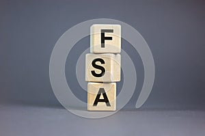 FSA symbol. Concept word `FSA, flexible spending account` on cubes on a beautiful grey background. Business and FSA concept. Cop