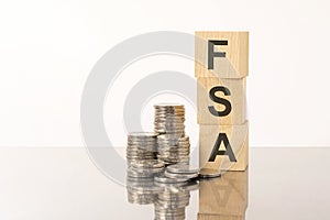 FSA - text on wooden cubes on white background with coins