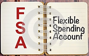 FSA word on notepad with wooden background