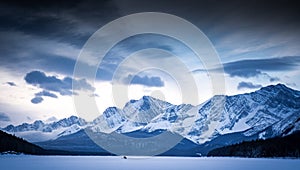 Fshermen stand in the middle of the frozen Kananaskis Lake surrounded by the Canadian Rocky Mountains in Alberta Canada