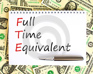 FTE Full time equivalent symbol. Concept words FTE Full time equivalent on white note. Dollar bills. Beautiful background from