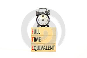 FTE Full time equivalent symbol. Concept words FTE Full time equivalent on wooden block. Beautiful white table white background.