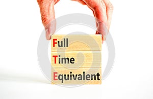 FTE Full time equivalent symbol. Concept words FTE Full time equivalent on wooden block. Beautiful white table white background.