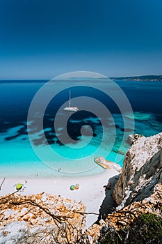 Fteri beach, Cephalonia Kefalonia, Greece. White catamaran yacht in clear blue sea water. Tourists on sandy beach near