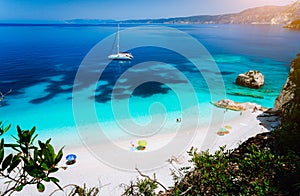 Fteri beach, Cephalonia Kefalonia, Greece. White catamaran yacht in clear blue sea water. Tourists on sandy beach near photo