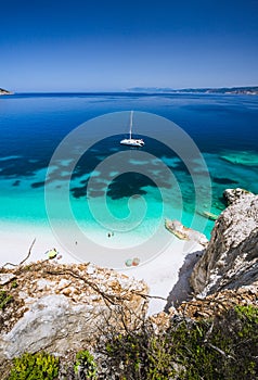 Fteri beach, Cephalonia Kefalonia, Greece. White catamaran yacht in clear blue sea water. Tourists on sandy beach near photo