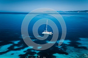 Fteri beach Kefalonia, Greece. White catamaran yacht in clear blue transparent sea with dark pattern water surface photo