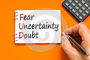 FUD fear uncertainty doubt symbol. Concept words FUD fear uncertainty doubt on white note on a beautiful orange table orange