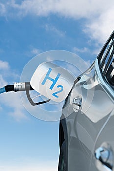 Fuel cell car with connected hydrogen fueling nozzle on a background of blue sky..