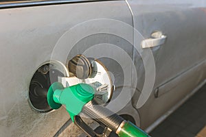 Fuel dispenser, green nozzle refueling car at the pump in gas station, close up