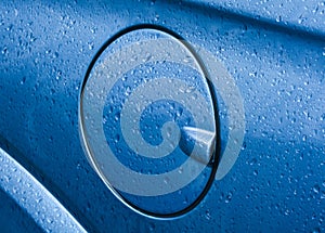 Fuel filler cap of metalic blue car after raining.