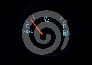 The fuel gauge on the black background showing that the tank is almost empty and it is  time to refuel