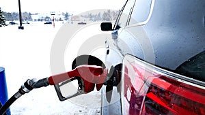 Fuel nozzle, filling gas tank of car during winter snow storm