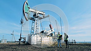 Fuel pumping derrick and two inspectors talking near it