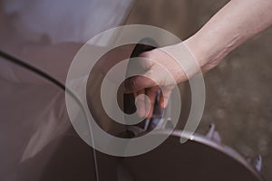 The fuel tank of the car is close-up. Woman fills up the car with fuel and closes the tank