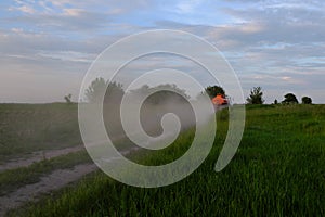 A fuel truck rushing along a dirt road leaving behind clouds of dust