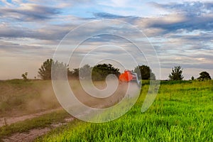 A fuel truck rushing along a dirt road leaving behind clouds of dust