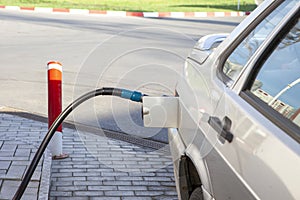 Fueling car with petrol pump at a gas station.