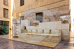 Fuente de las Flores, simple stone drinking water fountain in the old city center of Malaga Plaza de las Flores,Andalusia, Spain